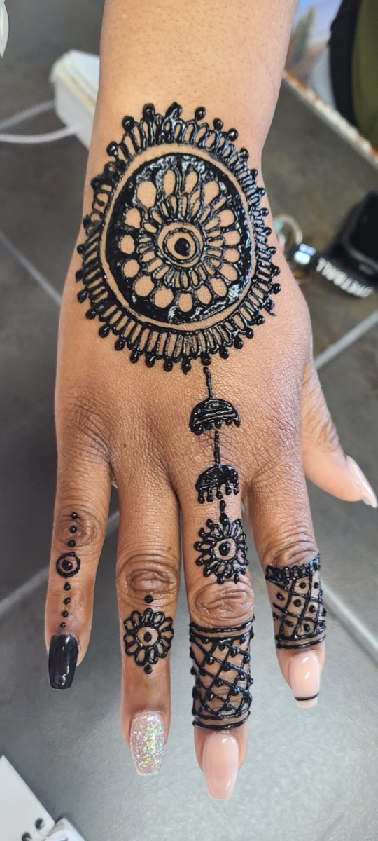 Detailed henna mandala design across the hand